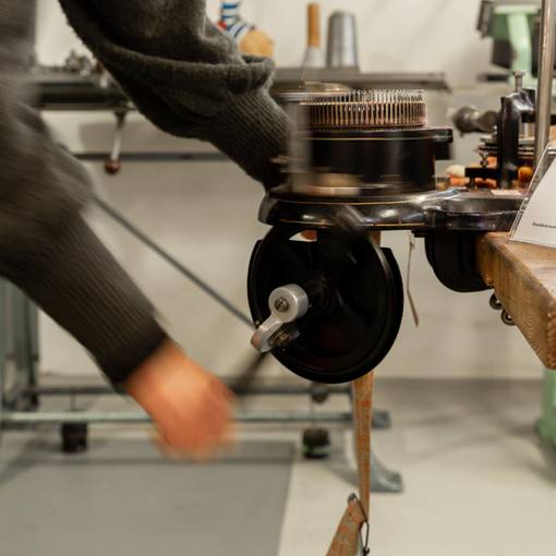 eine historische Kleinrundstrickmaschine wird mit der Hand angetrieben